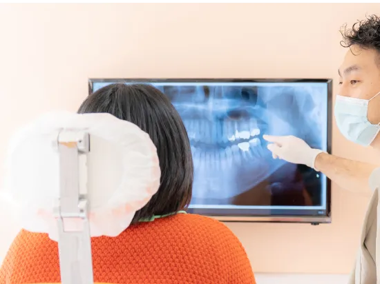 エックス線写真を見ながら歯科医が説明をしている写真