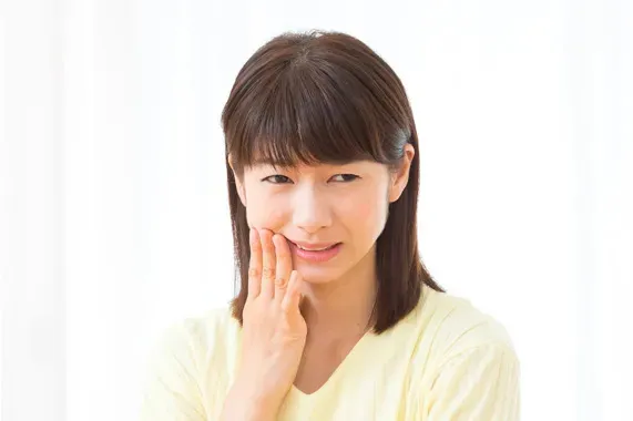 歯が痛くて奥歯付近をおさえている女性